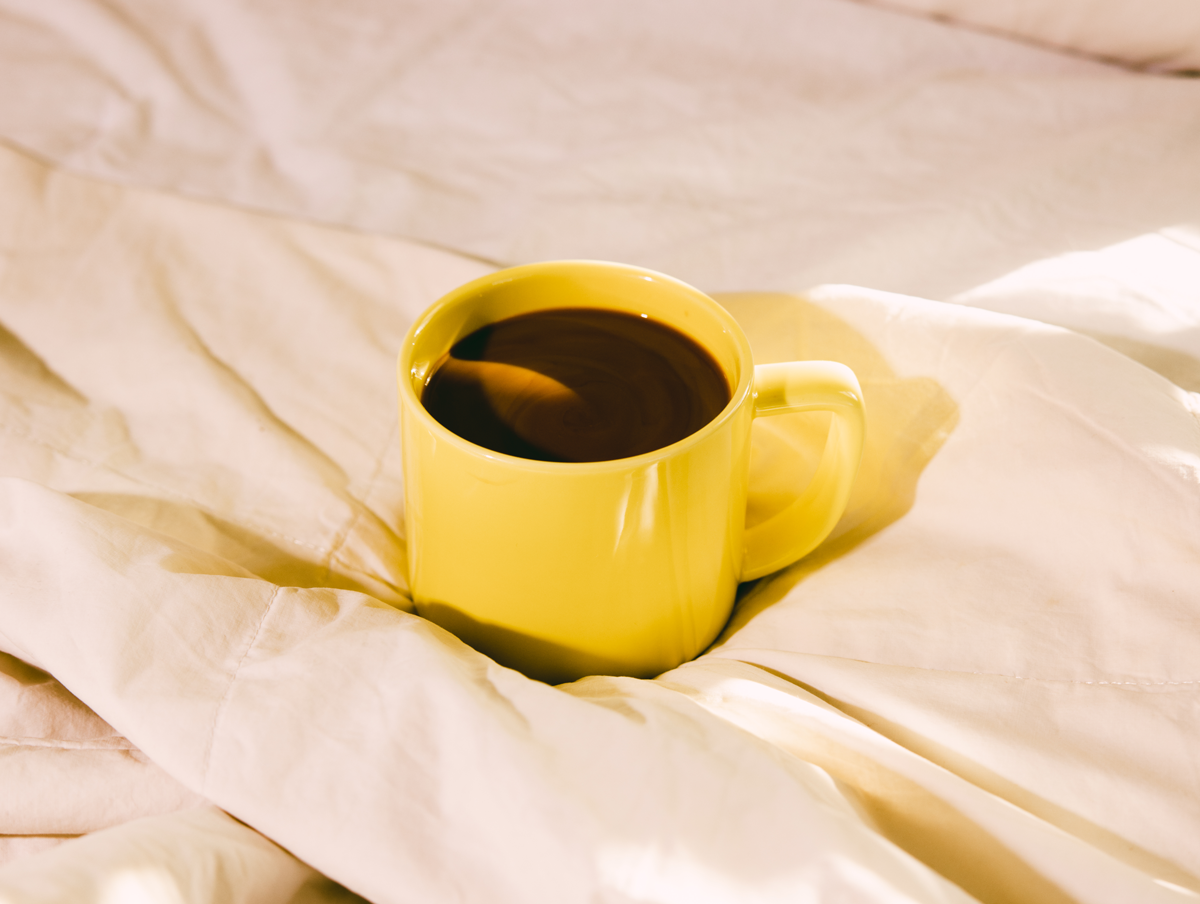 A mug of coffee on a bed