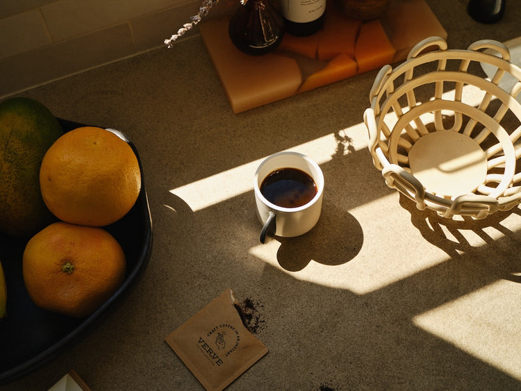 a cup of coffee and oranges on a table